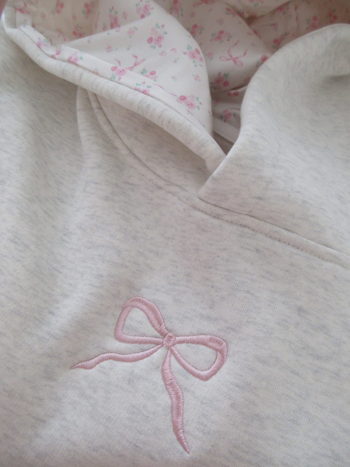 Sudadera Gris Jaspeada con Lazo Bordado Cómoda para Mujer con Capucha, Manga Larga, Forro Floral y Estilo Oversize de Punto